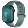 A teal-cased Apple Watch with a light green silicone sport band on a wrist.