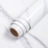 A roll of white self-adhesive marble wallpaper lying on a white marble surface.