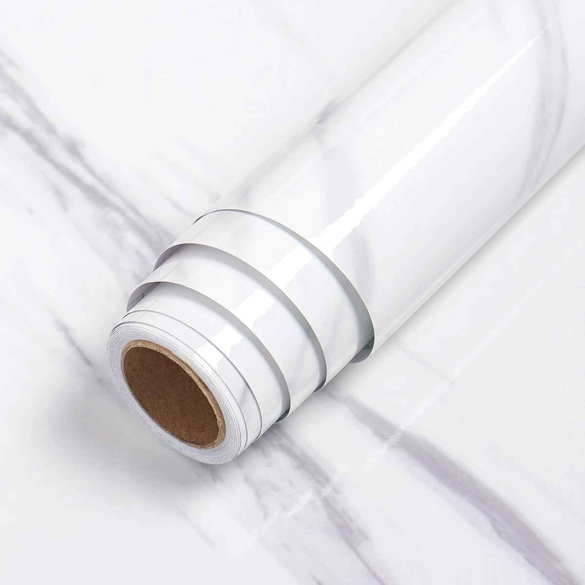 A roll of white self-adhesive marble wallpaper lying on a white marble surface.