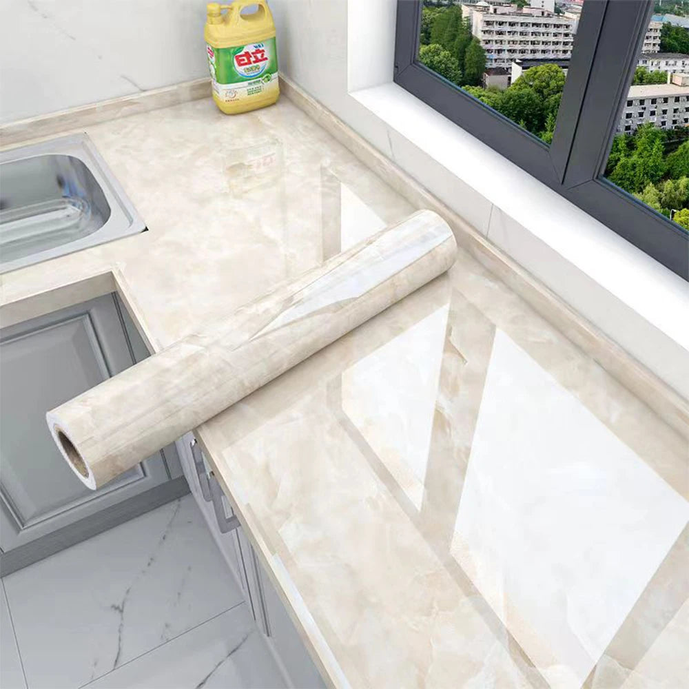 Roll of marble peel-and-stick film displayed on a kitchen countertop with a window view.