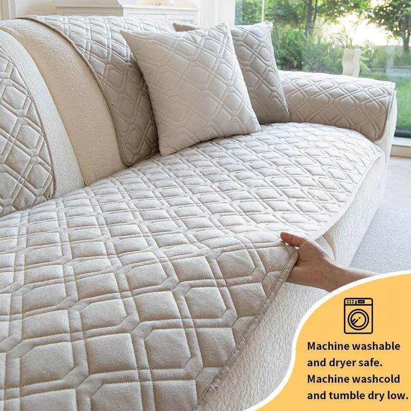 A beige quilted anti-slip sofa cover with a geometric pattern shown on a light-colored sofa.