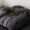 Black red plaid bedding set with a speckled duvet cover, flat sheet, and pillowcases on a dark surface.