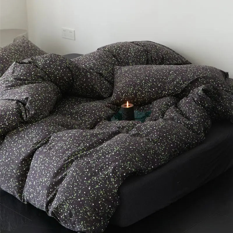 Black red plaid bedding set with a speckled duvet cover, flat sheet, and pillowcases on a dark surface.