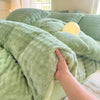 A hand is touching a soft, light green plush fleece duvet cover with a rabbit design on a bed.