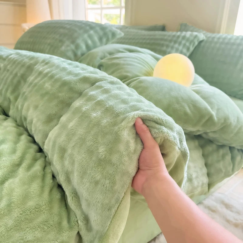 A hand is touching a soft, light green plush fleece duvet cover with a rabbit design on a bed.
