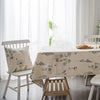 A light beige cotton-linen tablecloth with a rustic fern print displayed on a white wooden table.