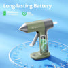 A silver and olive green cordless hot glue gun with a glowing blue nozzle rests on a circular surface.