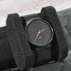 A black portable leather watch is shown inside a padded travel case with soft lining.