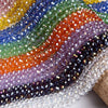 A close-up of multicolored faceted crystal glass spacer beads arranged in a wavy line.