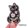 Black embroidery patch of a cat face with white flowers and green leaves