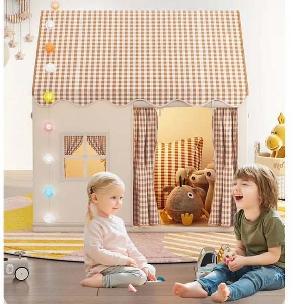 A young girl sits in front of a wooden foldable princess castle play tent decorated with gingham fabric and curtains.