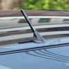A close-up view of a carbon fiber short radio antenna mounted on the roof of a car.