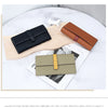 A display of various women's cowhide leather bifold wallets in brown, navy blue, and beige tones on a light wooden surface.