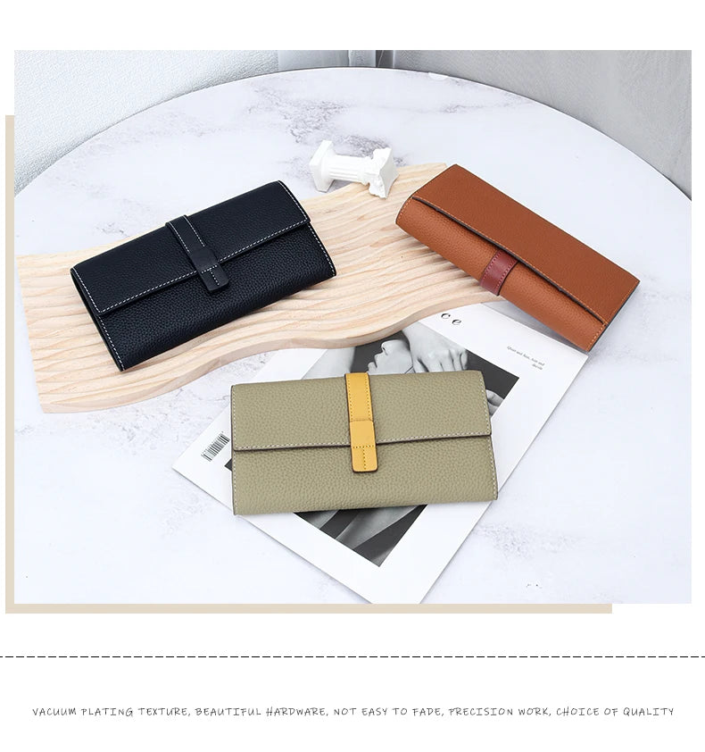 A display of various women's cowhide leather bifold wallets in brown, navy blue, and beige tones on a light wooden surface.