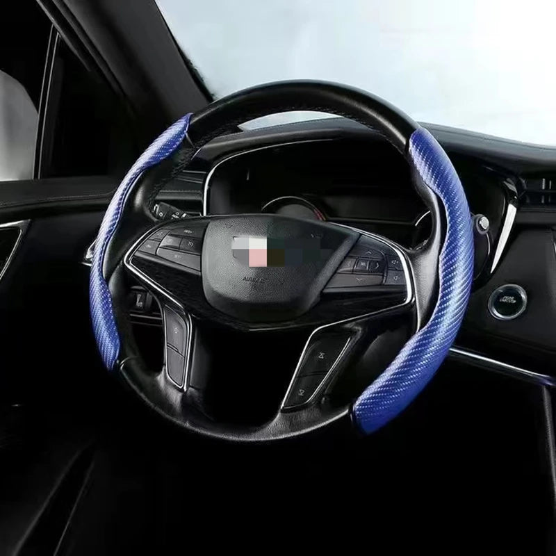 A black steering wheel with blue stitching and a carbon fiber trim is shown inside a car interior.