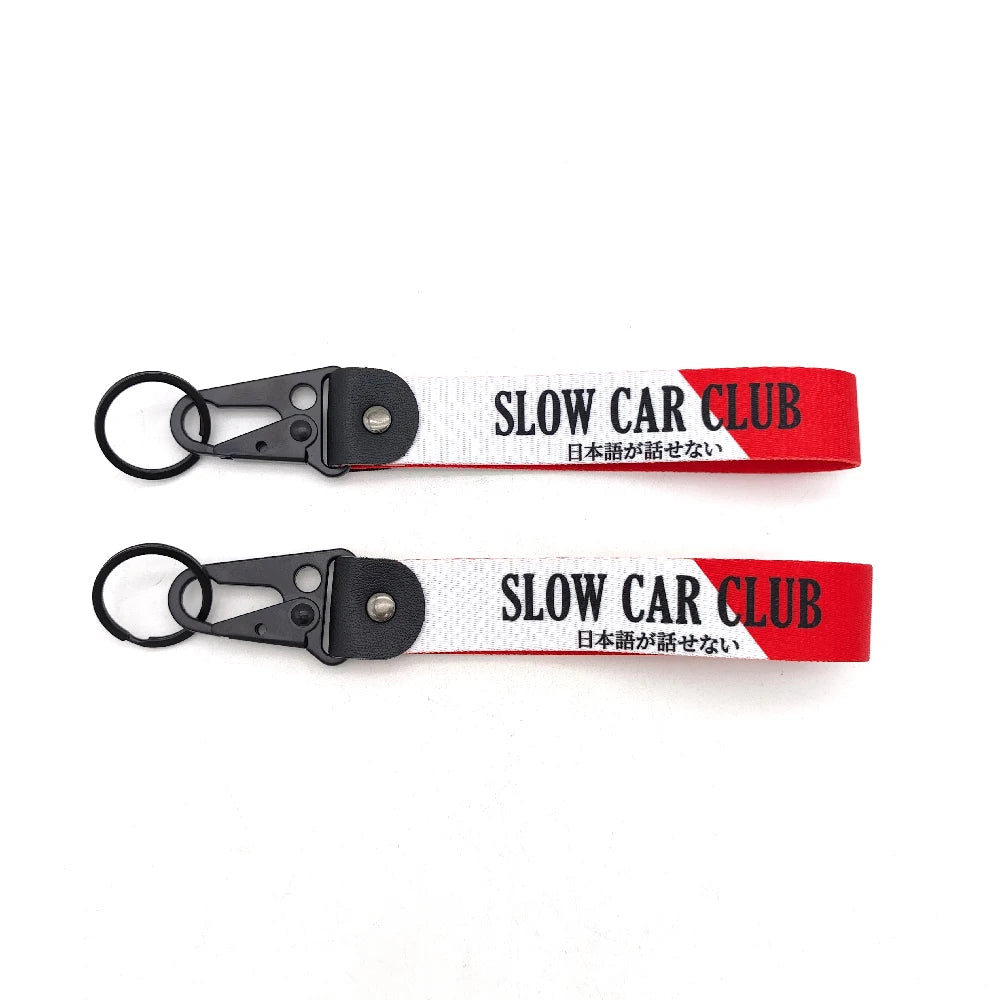 Red and white nylon keychain with a steel clip featuring the text SLOW CAR CLUB in English and Japanese