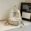 A light beige Japanese corduroy casual backpack is displayed on a white surface next to a framed sign.