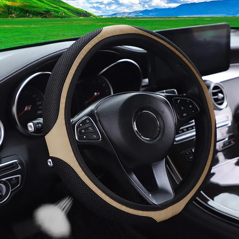 Interior view of a car showing a black steering wheel with tan leather accents and diamond stitching.