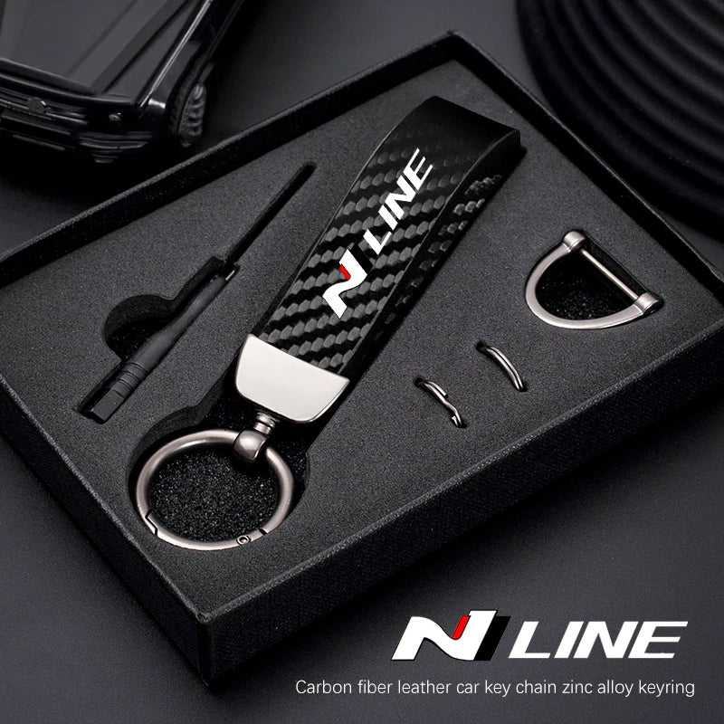 A black box displaying a carbon fiber style leather car key chain with a silver swivel buckle.