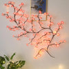 String lights shaped like flower vines with pink cherry blossoms illuminating a framed picture.
