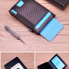Schwarze Pop-up-Karte-Wallet mit Geldclip und blauem Kartenhalter auf Holzoberfläche.