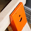 Orange heavy-duty steel workbench brackets attached to a light wood surface.