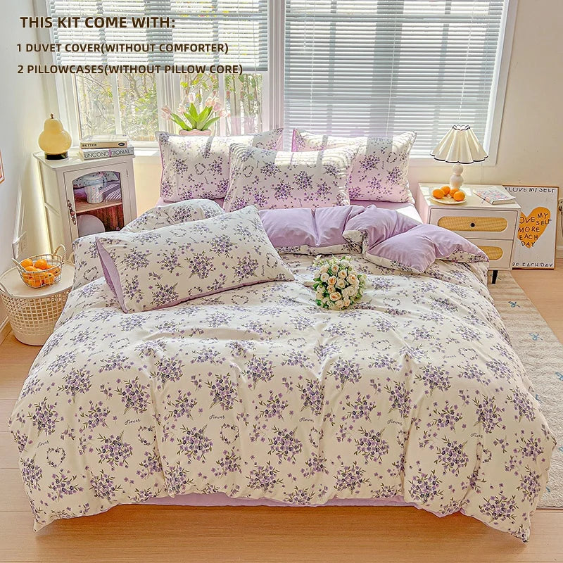 A lavender floral duvet cover set displayed on a bed with pillows and accessories.