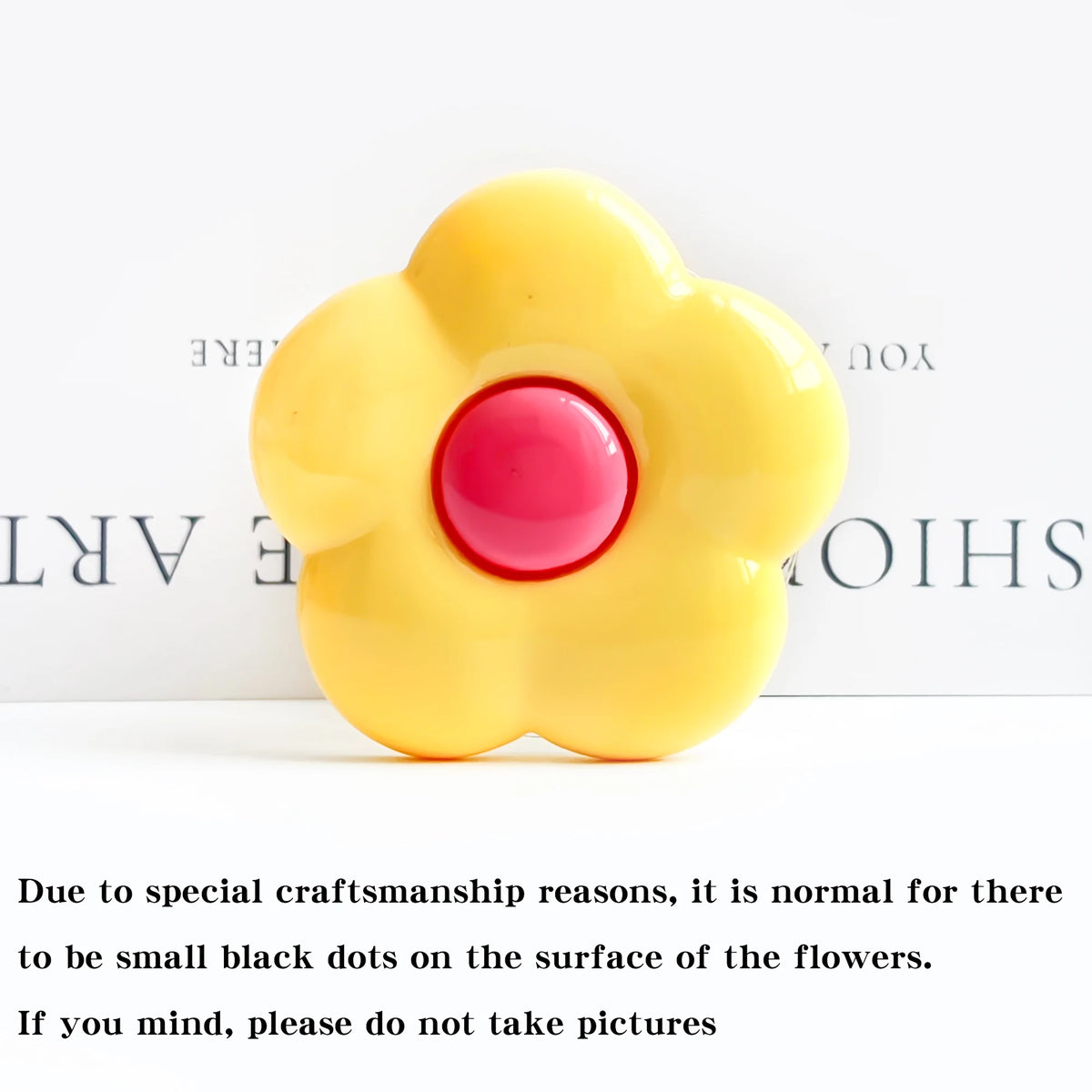 A yellow flower-shaped phone grip stand with small black dots on the surface.