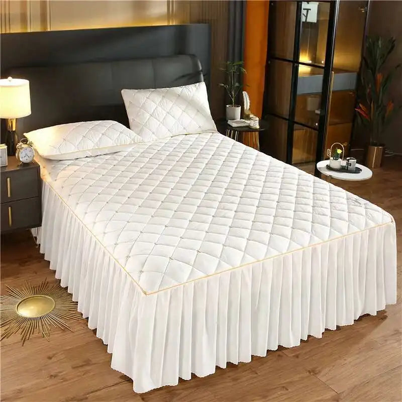 White quilted bed skirt with a gold trim on a bed in a modern bedroom setting.