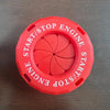 A red circular button cover for a start/stop engine mechanism with a rotating design.
