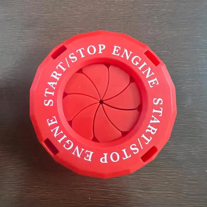 A red circular button cover for a start/stop engine mechanism with a rotating design.