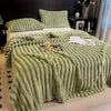 A thick, light green faux fur blanket with vertical ribbed texture is draped over a bed.