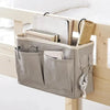 A beige hanging storage organizer with cotton pockets is displayed on a wooden shelf.