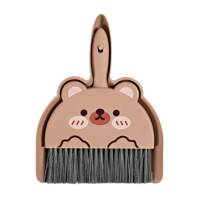 A compact cartoon broom and dustpan set in a matte pink color for desk and tabletop cleaning.