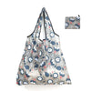 A reusable shopping tote bag featuring a gray and blue winter forest pattern, with an attached small carry pouch.