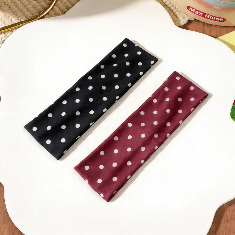 Un bandeau en tissu marron avec des pois blancs est posé en diagonale sur une surface blanche.