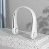 A white hands-free bladeless neck fan with a digital display is shown resting on a textured surface.