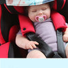 A baby is secured in a red car seat with a head band and safety strap.