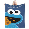 A dark blue blanket featuring a cartoon cookie monster face with large eyes and orange and black features.