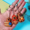 A hand holds an adorable capybara keychain charm with a wooden body and orange ear, attached to a silver ring.