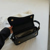 Black vintage leather crossbody bag with a flap closure resting on a white surface.