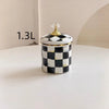 A small white and black checkerboard porcelain storage jar with a gold lid, labeled 1.3L.