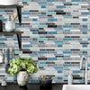 A gray and blue subway tile backsplash featuring various rectangular tiles in shades of light gray, dark gray, and teal.