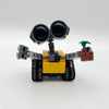 Set de bloques de construcción mini robot amarillo y gris con grandes ojos negros y accesorio de brazo verde.