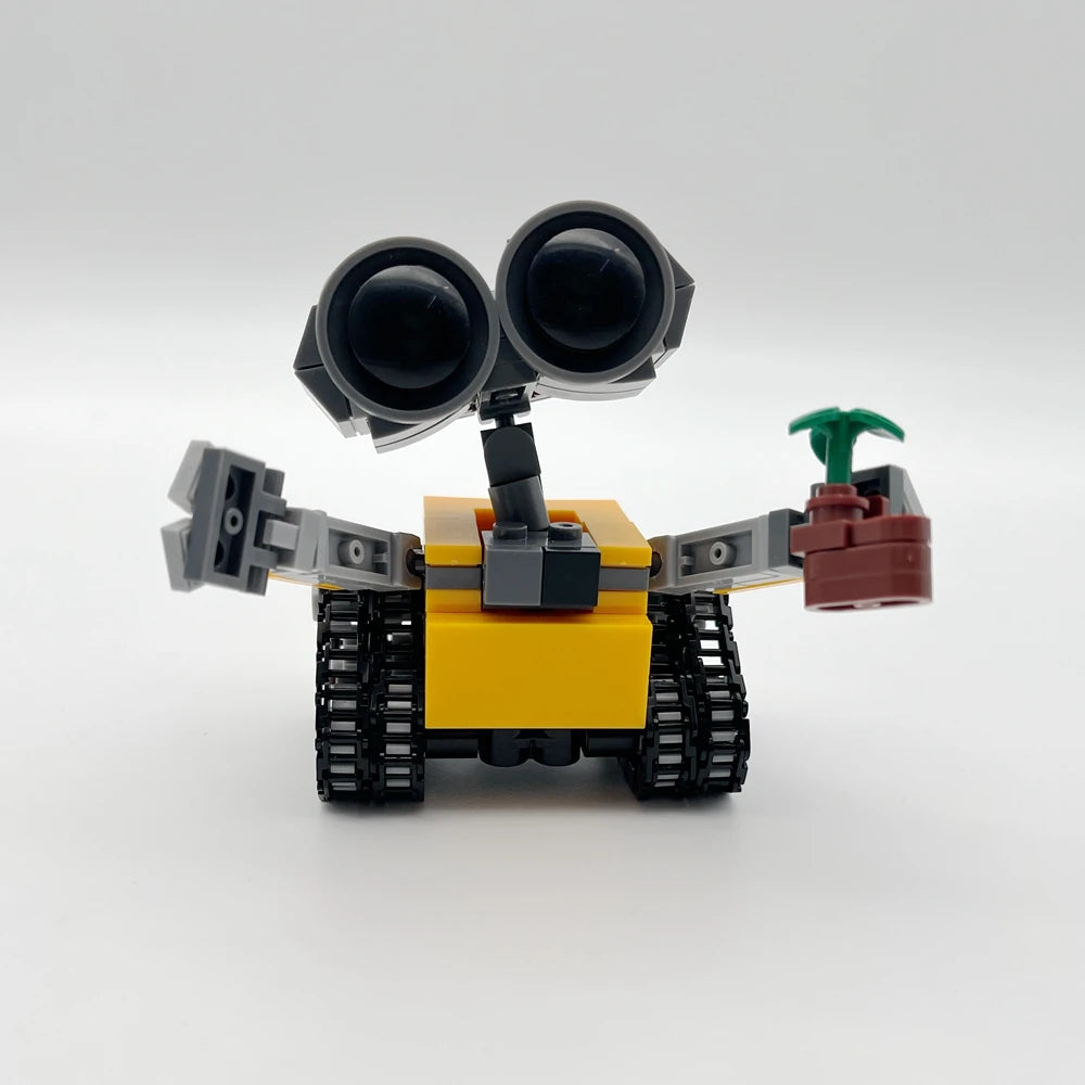 Set de bloques de construcción mini robot amarillo y gris con grandes ojos negros y accesorio de brazo verde.