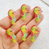 Hand holding several yellow and pink resin charms shaped like sleeping cats