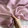 Close-up of flowing light pink mulberry silk chiffon fabric being gathered by a hand