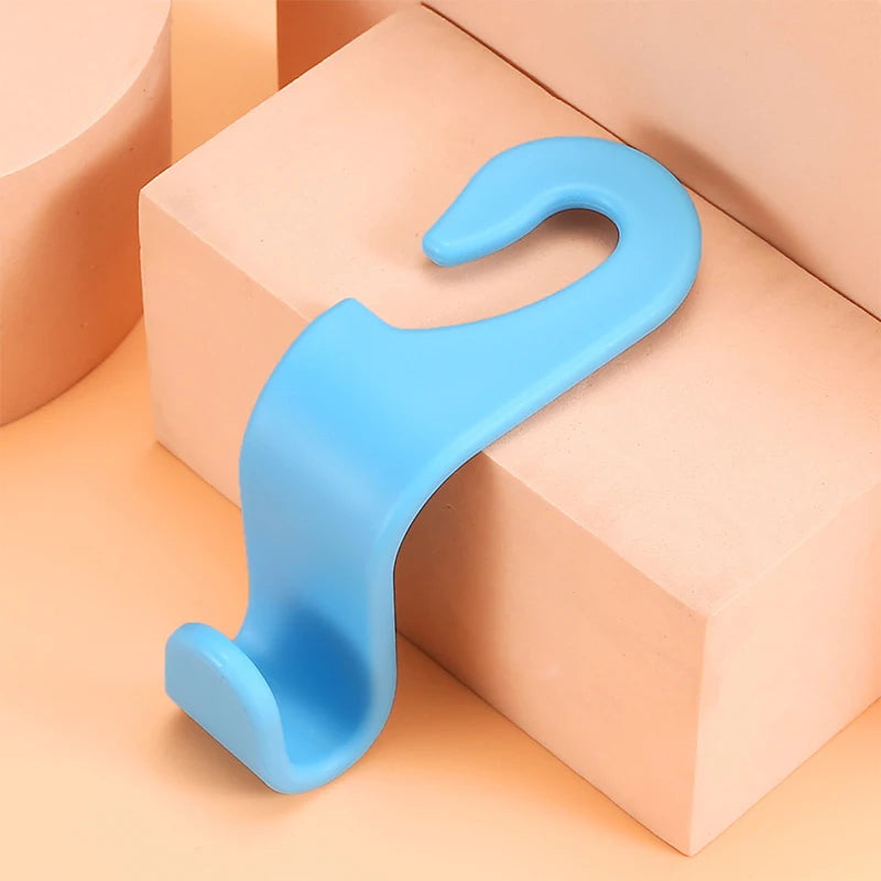 A pair of light blue universal car seat headrest hooks resting on a peach-colored box.