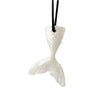 A white silicone sensory chew necklace pendant shaped like a fish, suspended by black string.