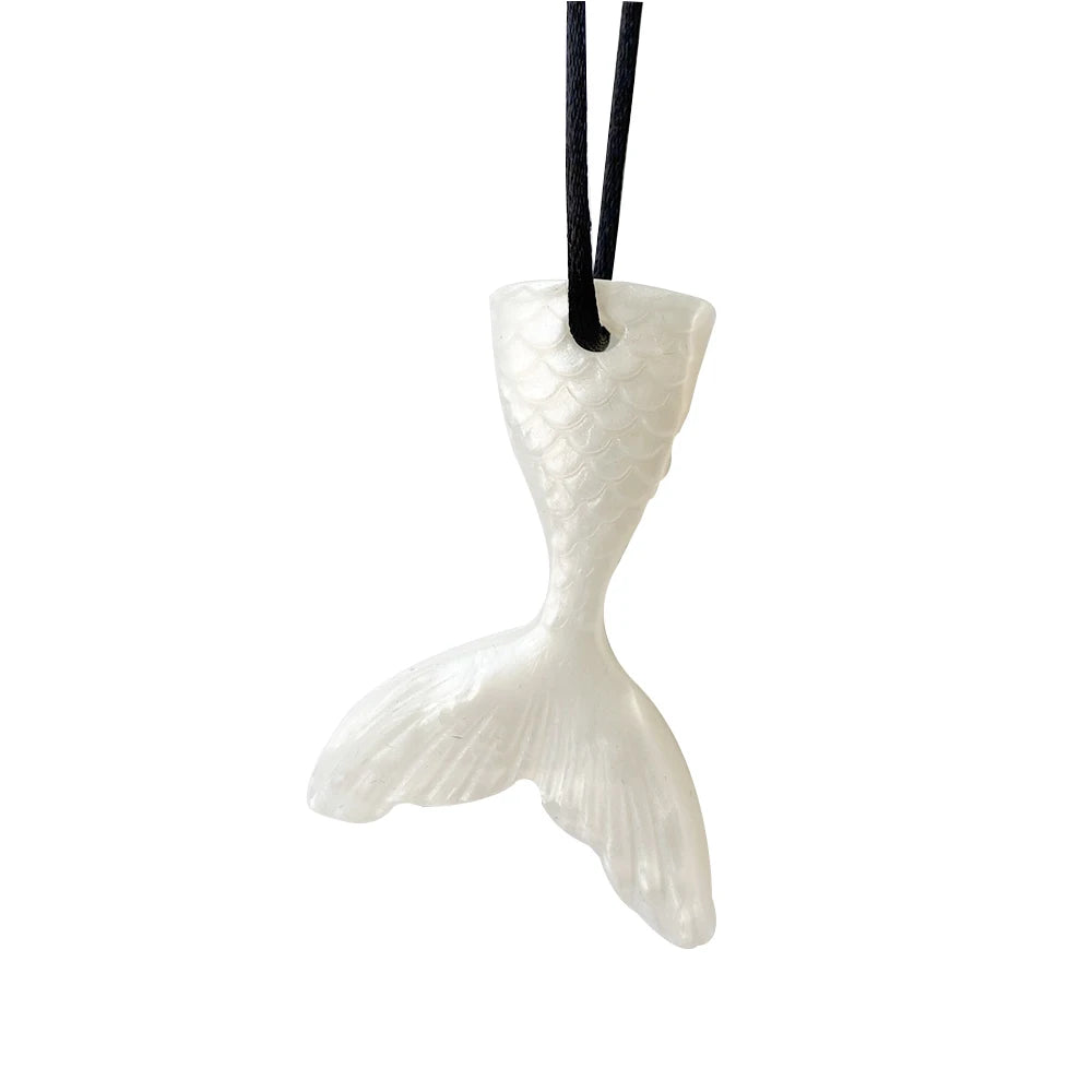 A white silicone sensory chew necklace pendant shaped like a fish, suspended by black string.